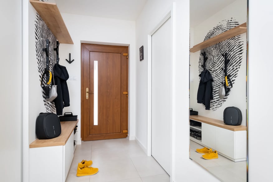 Moderní předsíň s dřevěným nábytkem a designovým vzorem.